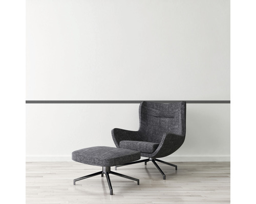 Sessel mit Fußhocker auf Holzboden vor einer weißen Wand