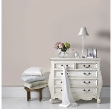 Dekoratives Schlafzimmer mit Kommode, Lampe und Kissenstapel