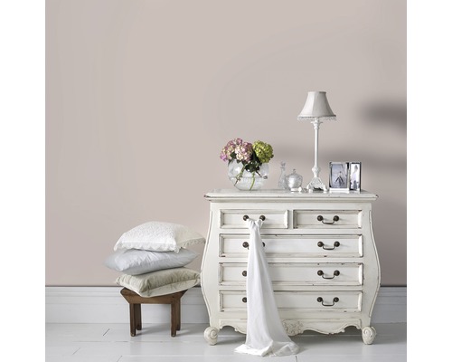 Dekoratives Schlafzimmer mit Kommode, Lampe und Kissenstapel