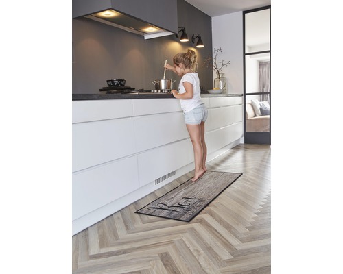 Küche mit Küchenläufer im Holzdesign und jungem Mädchen am Herd