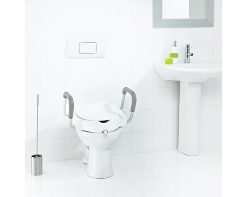Toilette mit Toilettensitzerhöhung und Haltegriffen in einem hellen Badezimmer