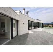 Außenbereich eines Hauses mit Steinboden, Terrasse und Glasgeländer