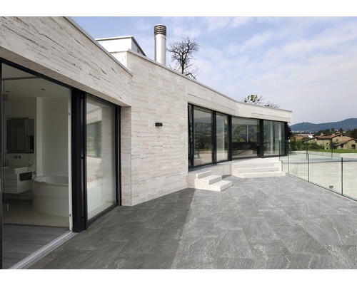 Außenbereich eines Hauses mit Steinboden, Terrasse und Glasgeländer