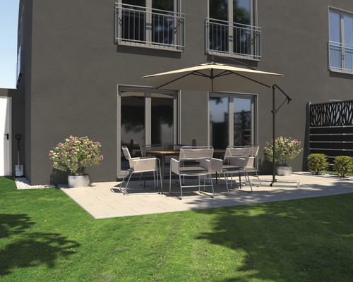 Terrasse mit Esstisch, Stühlen, Sonnenschirm und Bepflanzung vor einem Wohnhaus