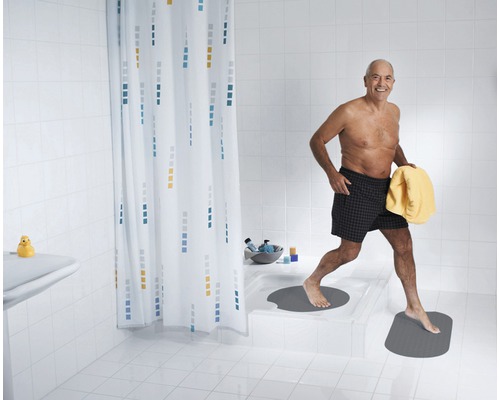 Helles Badezimmer mit Duschvorhang, Badematten und einer Person mit Handtuch