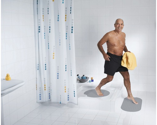 Mann verlässt mit einem Handtuch eine Dusche mit Duschvorhang und Badematten