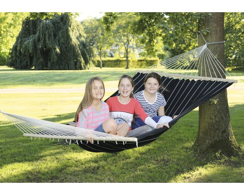 Drei Kinder sitzen in einer zwischen zwei Bäumen aufgehängten Hängematte.