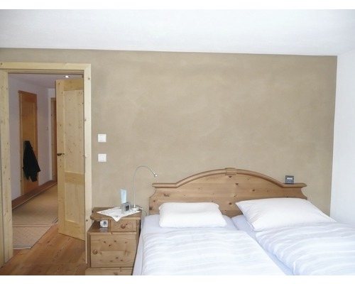 Schlafzimmer mit Holzbett, Nachttisch und offener Tür