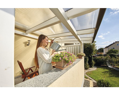 Eine Frau gießt Blumen auf einem Balkon mit transparentem Dach.