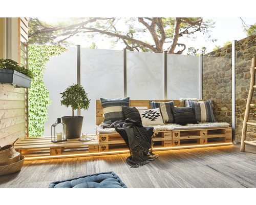 Terrasse mit Palettenmöbeln, Kissen, Pflanzen und Sichtschutz