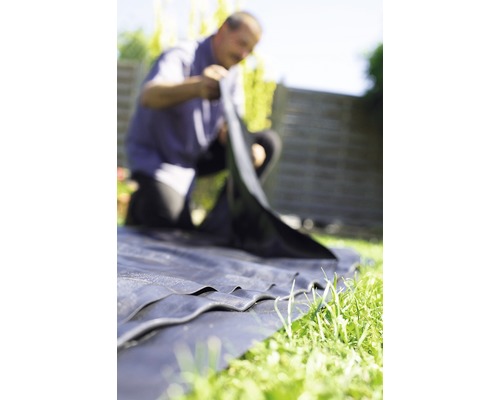 Mann verlegt Unkrautvlies im Garten