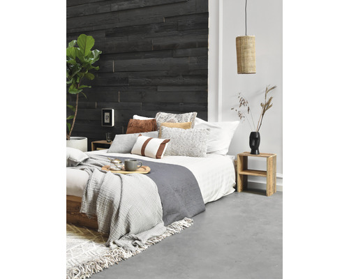 Schlafzimmer mit Holzwand, Bett, Kissen, Decken, Beistelltisch und Lampe