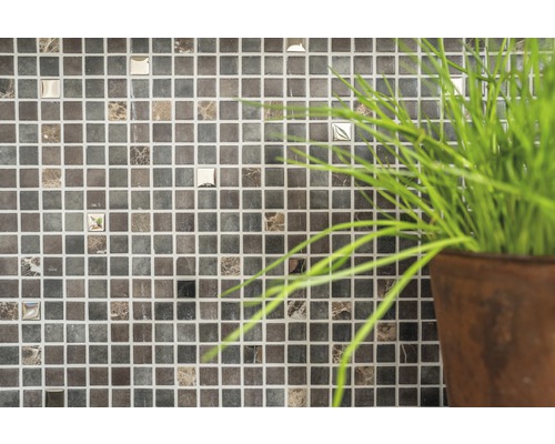 Nahaufnahme einer Wand mit Mosaikfliesen und Topfpflanze.