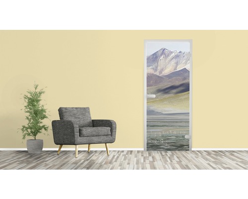 Wohnzimmer mit Sessel, Pflanze und Türposter mit Bergmotiv