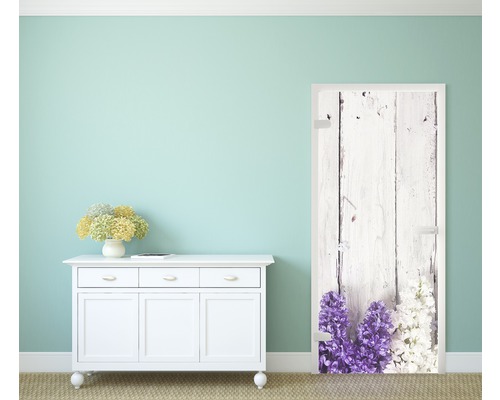 Szene mit einer Türfolie mit Holzmuster und Blumenmotiv neben einer Kommode.