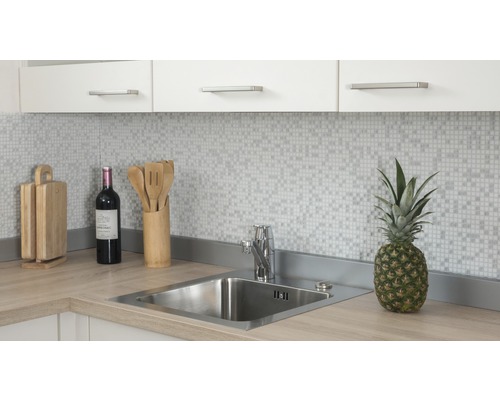 Küchenszene mit Spüle, Armatur, Schneidebrettern, Wein und Ananas