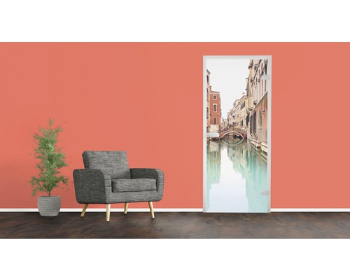 Zimmerszene mit Sessel, Zimmerpflanze und Türposter mit Venedig-Motiv