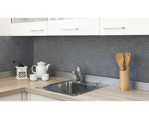 Küchenszene mit Spüle, Armatur, Kaffeemühle, Geschirr und Küchenutensilien vor Mosaikhintergrund