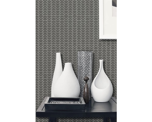 Dekoratives Wohnzimmer mit gemusterter Tapete, verschiedenen Vasen und einem rechteckigen Tablett auf einem Tisch.