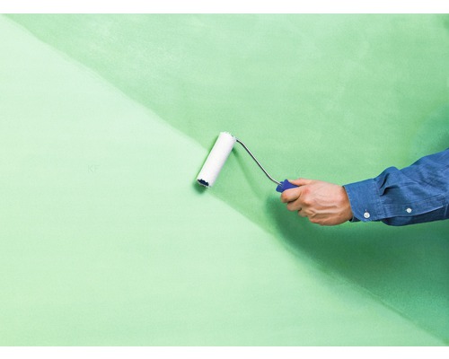 Eine Wand wird mit einer Farbwalze gestrichen.