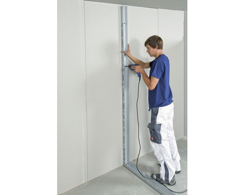 Mann befestigt Metallständerwerk mit Bohrmaschine an einer Wand