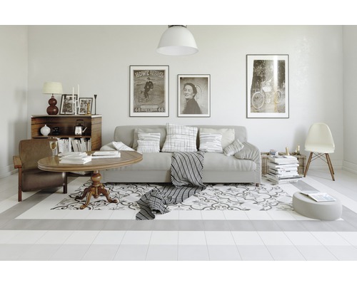 Wohnzimmer mit Sofa, Sessel, Tisch und dekorativem Teppich auf hellem Boden