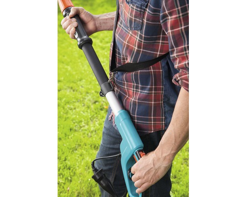 Mann bedient eine elektrische Heckenschere im Garten.