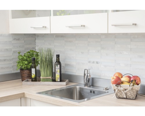 Küchenspüle mit Armatur, Dekoration und Lebensmitteln auf einer Arbeitsplatte vor einer Fliesenspiegel