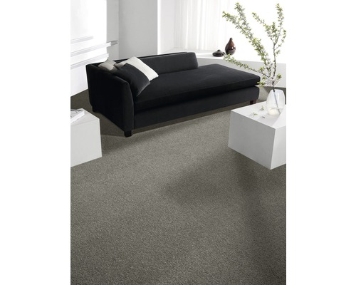 Heller Raum mit grauer Auslegware, schwarzer Couch und weißen Beistelltischen