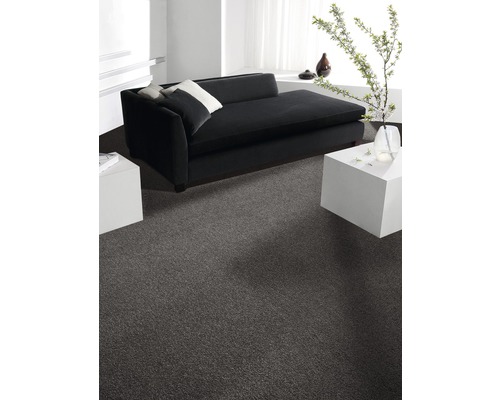 Wohnzimmer mit grauer Auslegeware, schwarzem Sofa und weißen Tischen