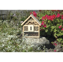 Insektenhotel aus Holz im Garten zwischen Blumen und Pflanzen