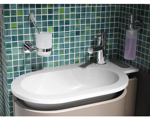 Badezimmerwaschtisch mit Armatur, Seifenspender und Zahnputzbecher vor Fliesenwand