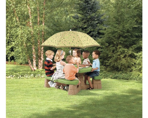 Kinder sitzen an einem Picknicktisch mit Sonnenschirm im Garten.