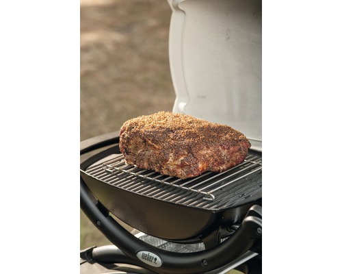 Bratenstück auf einem Grillrost über einem Grill, Weber Logo sichtbar