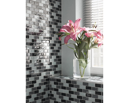 Wand mit rechteckigen Mosaikfliesen und Blumen in einer Vase auf dem Fensterbrett
