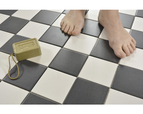 Quadratische Fliesen in Schachbrettmuster mit Stück Seife und Füßen