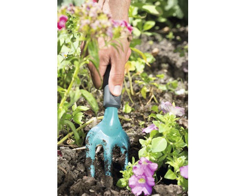 Gartenarbeit mit einer kleinen Gartenkralle im Blumenbeet.