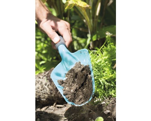 Eine Handschaufel mit Erde im Garten.