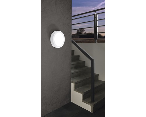 Eine runde Wandleuchte neben einer Treppe in einem Haus.