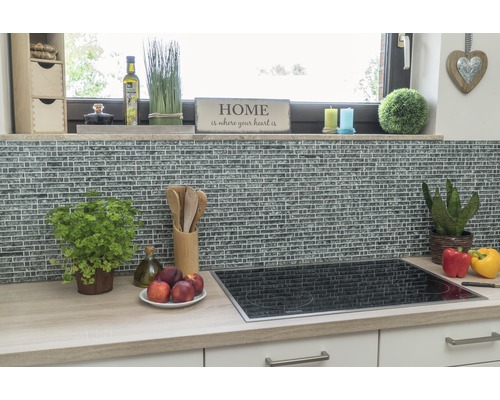 Küchenszene mit Mosaikfliesenwand, Kochfeld und Küchenutensilien auf einer Arbeitsplatte.