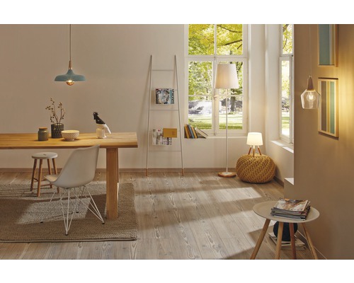 Helles Wohnzimmer mit Holztisch, Stühlen, Regalleiter und verschiedenen Lampen