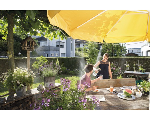 Szene im Garten mit Sonnenschirm, Nebelsystem und Personen beim Essen