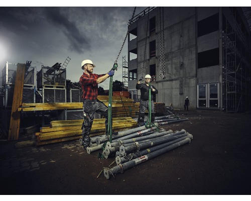Bauarbeiter beim Heben von Baustützen mit einem Kran auf einer Baustelle