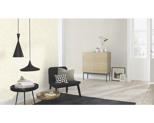 Wohnzimmer mit gemusterter Tapete, schwarzem Sessel, schwarzem Teppich und Hängelampe.