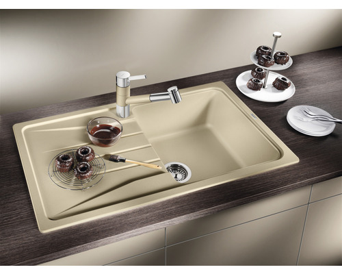 Spüle mit Abtropffläche, Wasserhahn, Siebkorb, Gebäck und Geschirr auf einer Küchentheke