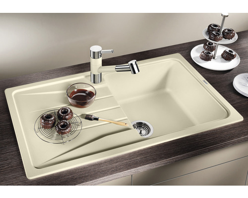 Beige Küchenspüle mit Abtropffläche, Armatur und Speisen auf einer Küchentheke