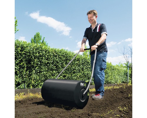 Ein Mann benutzt eine Gartenwalze von for.q im Garten.