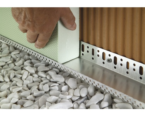 Detailansicht eines Fassadendämmprofils an einer Hauswand mit Kiesbett