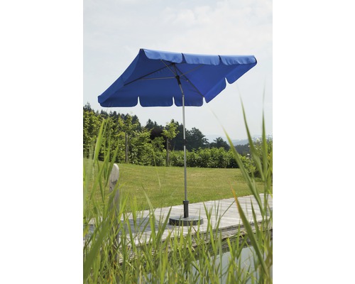Blauer Sonnenschirm auf einer Terrasse mit Rasen im Hintergrund.