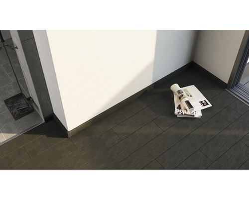 Detailansicht eines Raumes mit dunklen Bodenfliesen und einer Zeitschrift